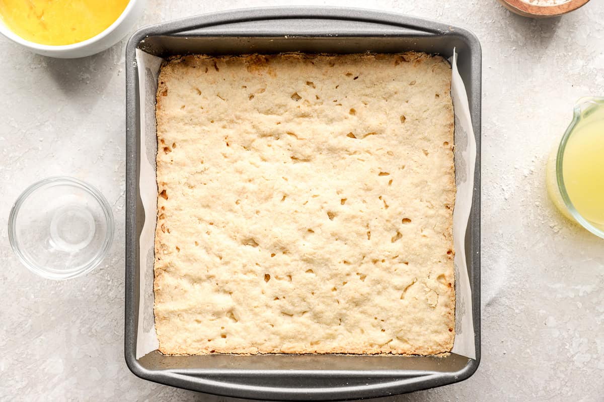 Partially baked gluten-free lemon bar crust in square baking pan