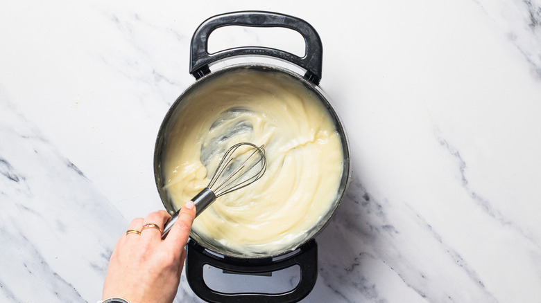 Whisking beurre manié into wine in fondue pot.