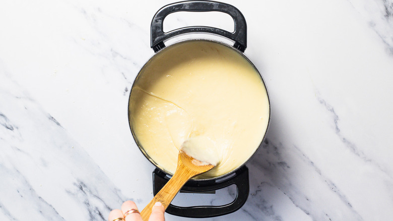 Stirrind fondue in a pot.