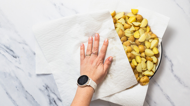Patting boiled potatoes dry.