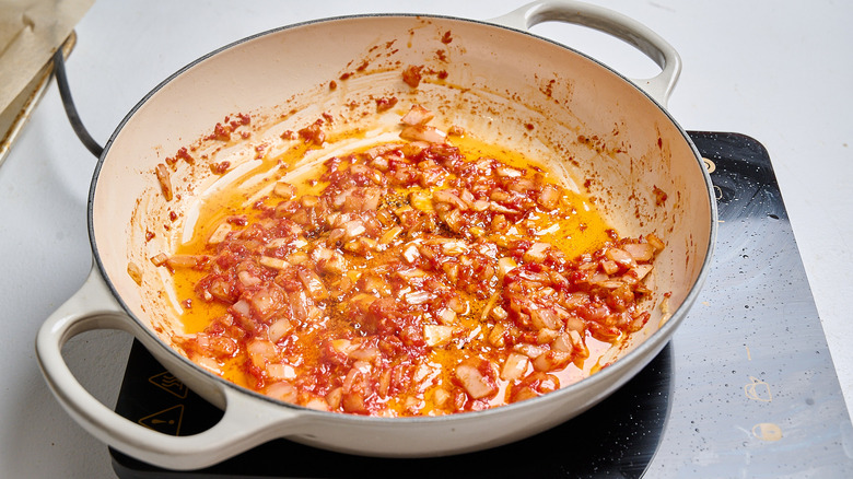 stirring tomato paste into the skillet with onion