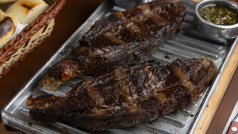 Two pieces of grilled skirt steak resting on a metal rack.