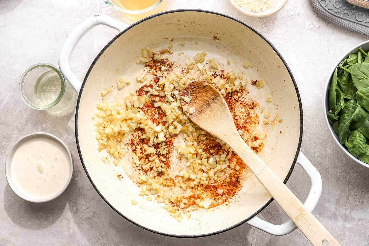 Chopped onion and garlic cooking in a skillet with browned bits on the bottom
