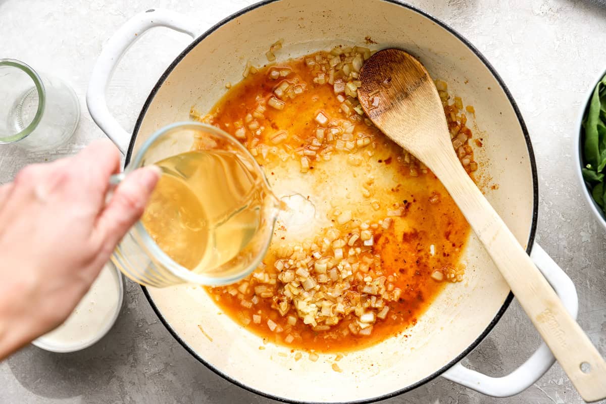 White wine being poured into the skillet to deglaze the pan
