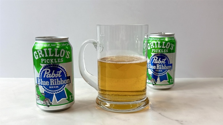 two cans of Pabst blue ribbon Grillo's pickle beer and a mug of beer