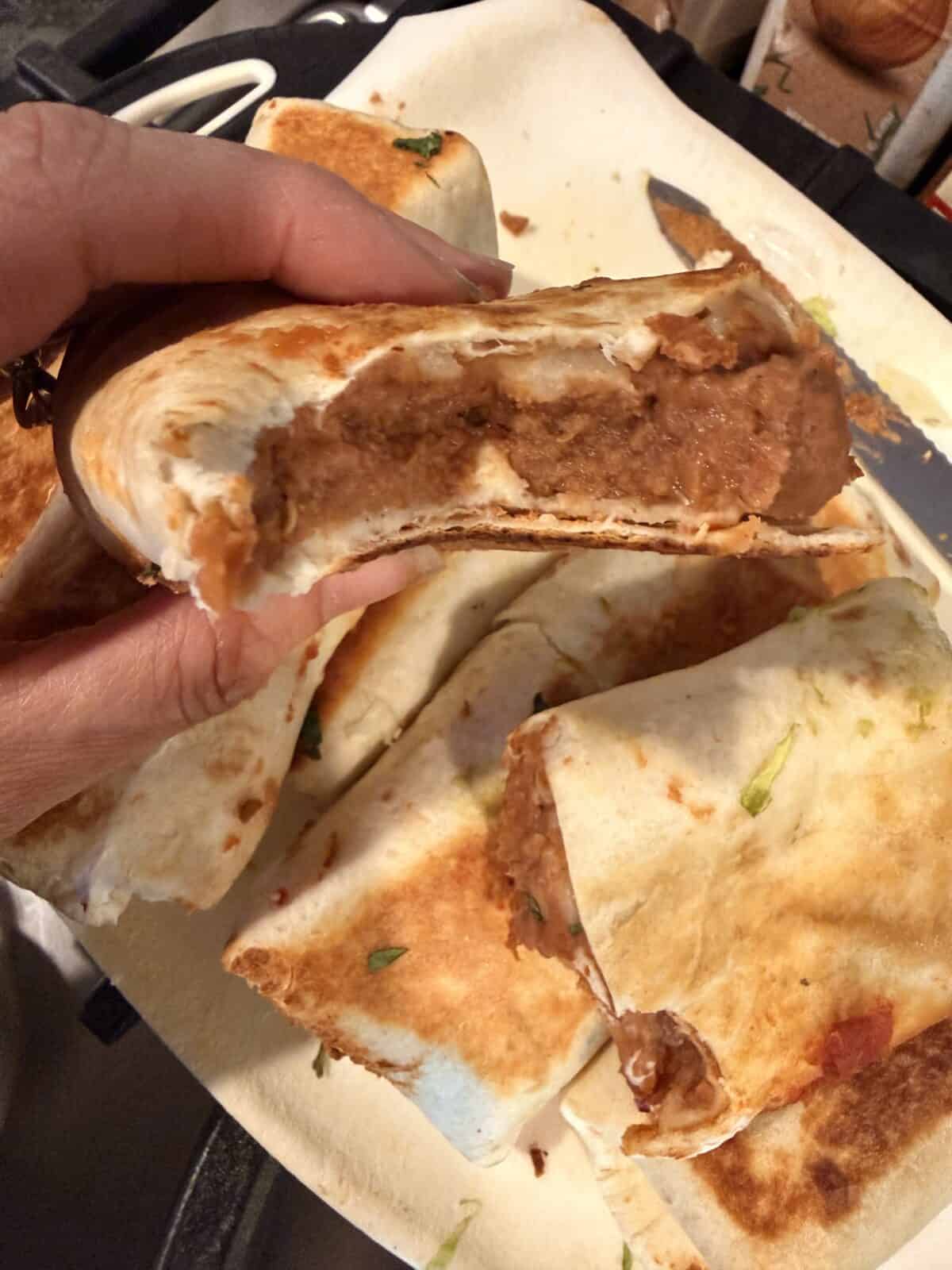 Close-up of a crispy bean and cheese burrito showing the creamy refried bean filling inside.