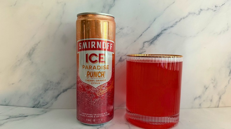 Can of Paradise Punch Smirnoff Ice next to glass of Smirnoff Ice on marble surface