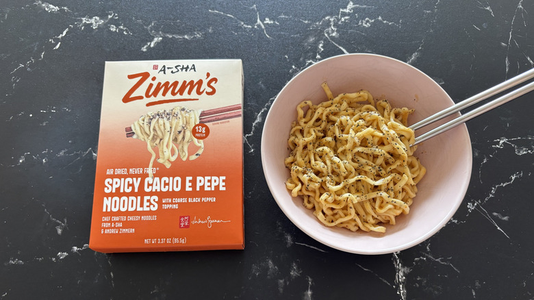 A-Sha/Zimm's spicy cacio e pepe noodle box next to prepared noodles in bowl
