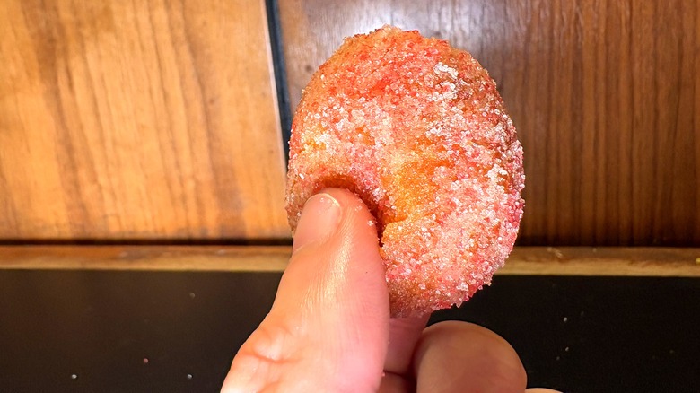 A Strawberry Cinnabon Delight behind held in between two fingers
