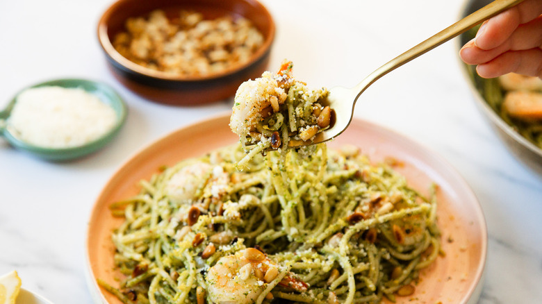 Lifting a fork of pasta and shrimp over plate.