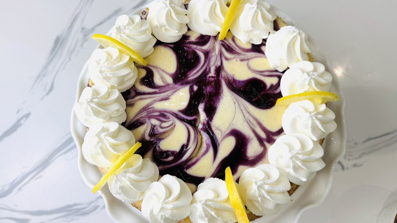 Blueberry lemon cheesecake topped with whipped cream and lemon slices