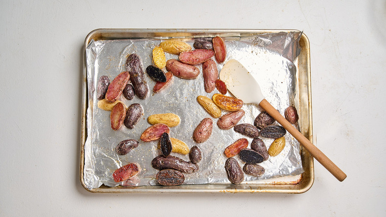 tossing potatoes on sheet tray