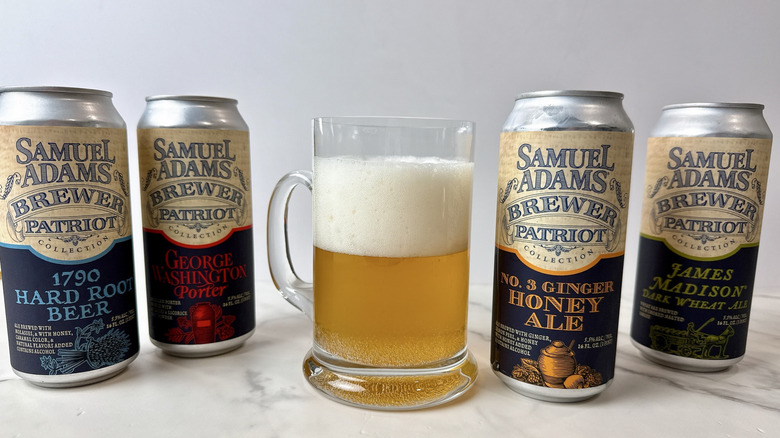four Sam Adams canned beers and one beer poured into a beer mug