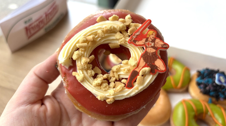 The new Krispy Kreme He-Man Caramel Crunch Doughnut with red frosting, cheesecake icing, graham crumbs and a He-Man plaque