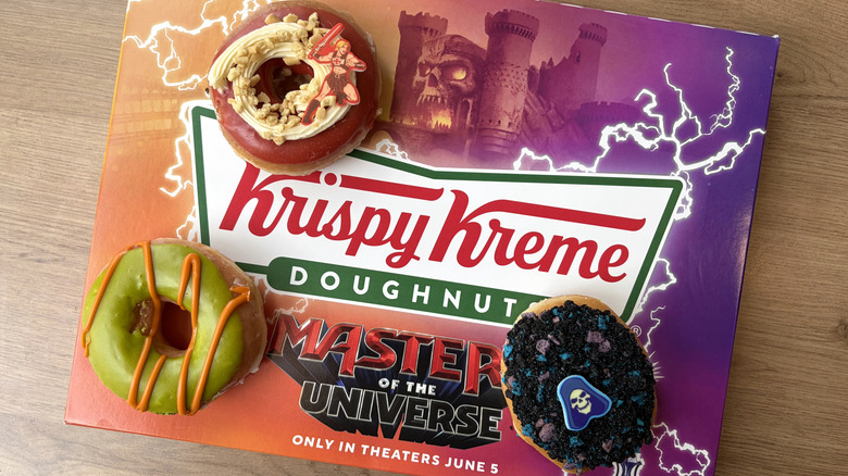 Three of the new Krispy Kreme Masters of the Universe Doughnuts on top of a branded box