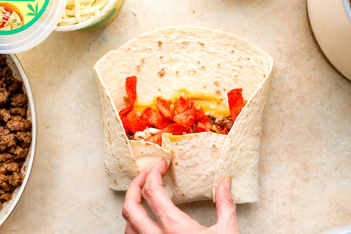 Folding a Flamin’ Hot grilled cheese burrito by tucking in the tortilla sides around the filling