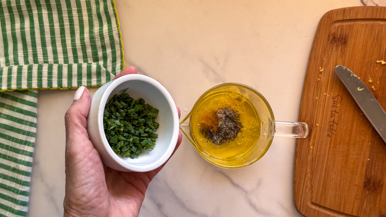 hand adding chives to bowl
