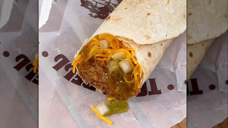Taco Bell Green Burrito on a wrapper filled with beans, cheese, onion, and green sauce