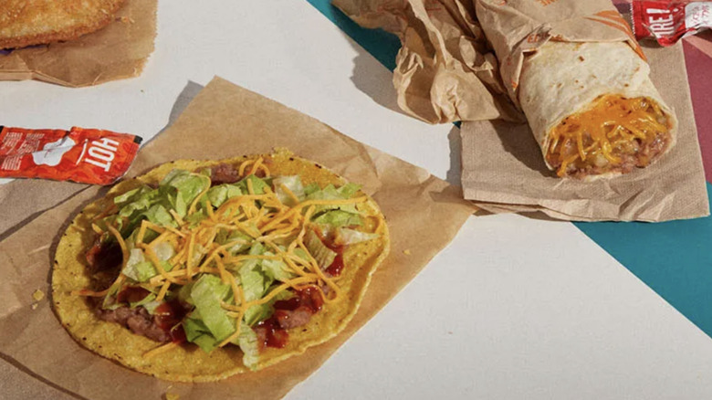 Taco Bell tostada and burrito on napkins with packets of sauce next to them