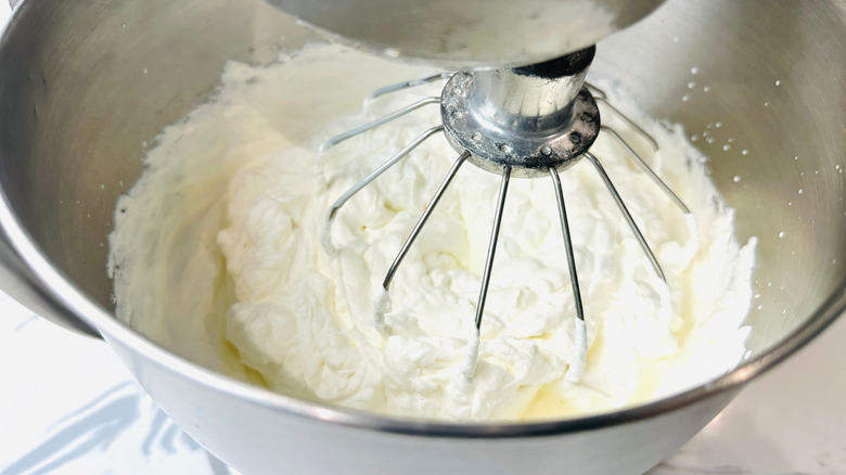 Whipped cream in stand mixer bowl with whisk attachment