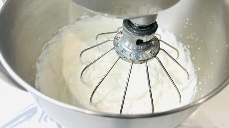 Whipped cream in stand mixer bowl with whisk attachment