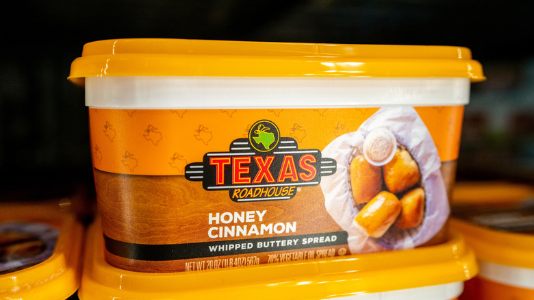 Several stacked tubs of Texas Roadhouse Honey Cinnamon Whipped Buttery Spread