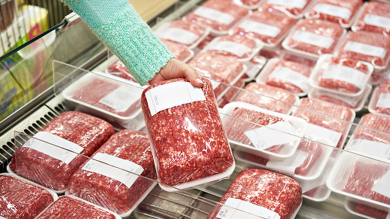 Buyer selecting a package of ground beef at a grocery store