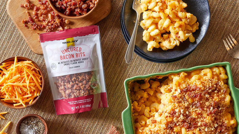 A bag of Trader Joe's Uncured Bacon Bits on a table with macaroni and cheese