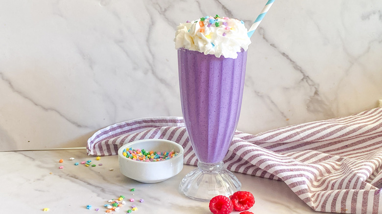 Purple Grimace shake with sprinkles and raspberries