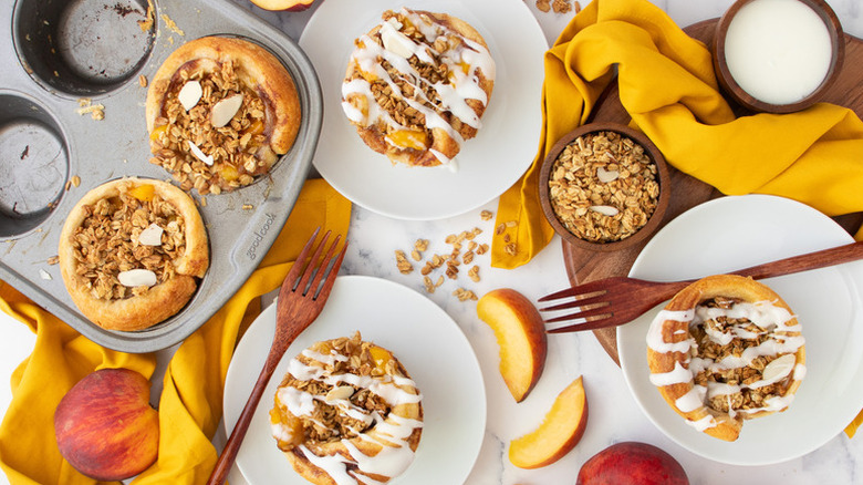 Peach cobbler cinnamon rolls in baking tin and served onto plates