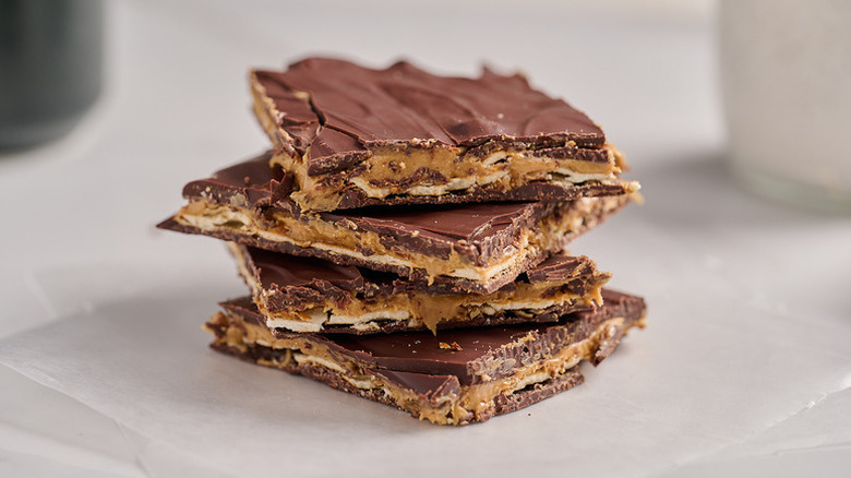 Chocolate date bark stacked on plate next to bowl of flaky sea salt