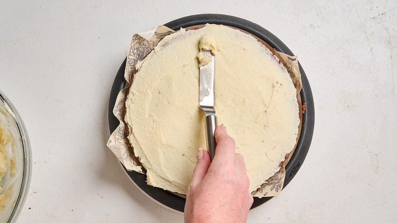 spreading frosting onto bottom layer of cake