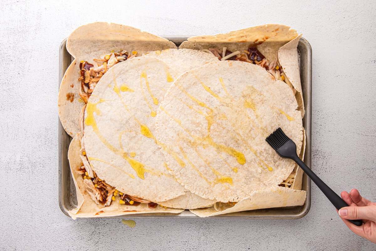 Top tortillas folded over the filling and brushed with oil before baking the sheet pan BBQ chicken crunchwrap.