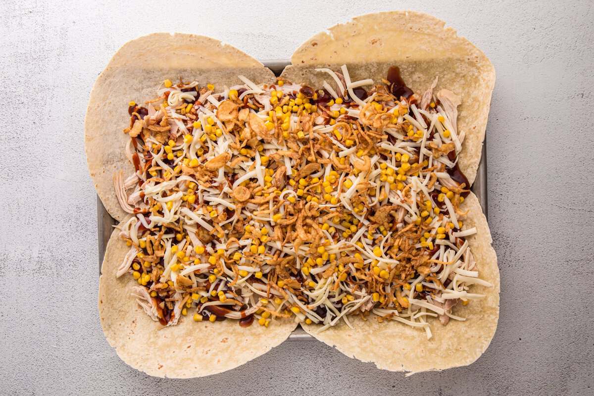 Crispy fried onions sprinkled over BBQ chicken, cheese, and corn filling for a sheet pan crunchwrap.