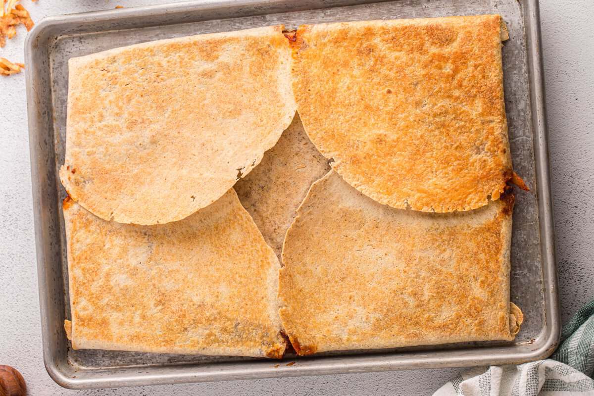 Top tortillas folded over the filling and brushed with oil before baking the sheet pan BBQ chicken crunchwrap.