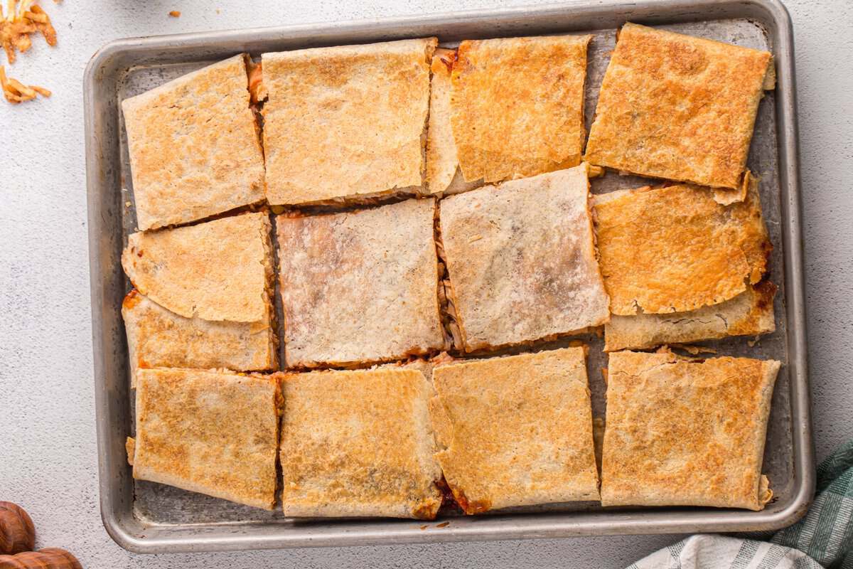 Sheet pan BBQ chicken crunchwrap sliced into squares for serving after baking.