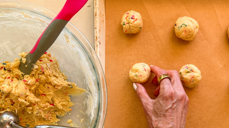 hand placing balls on baking sheet