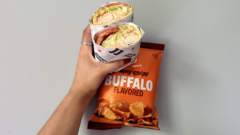 Hand holding Jimmy John's Buffalo Ranch Chicken Wrap and Buffalo-flavored chips