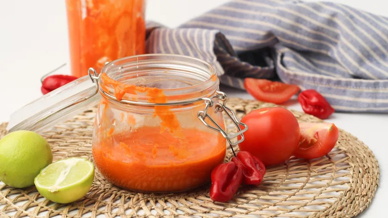 Chili-Lime Hot Sauce in glass jar with limes, peppers, and tomatoes