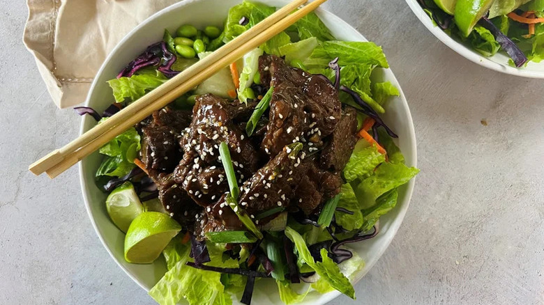 Mongolian Beef Salad with Ginger-Lime Vinaigrette in white bowl with chopsticks