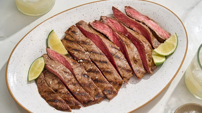 Margarita-Inspired Flank Steak on white plate with lime wedges