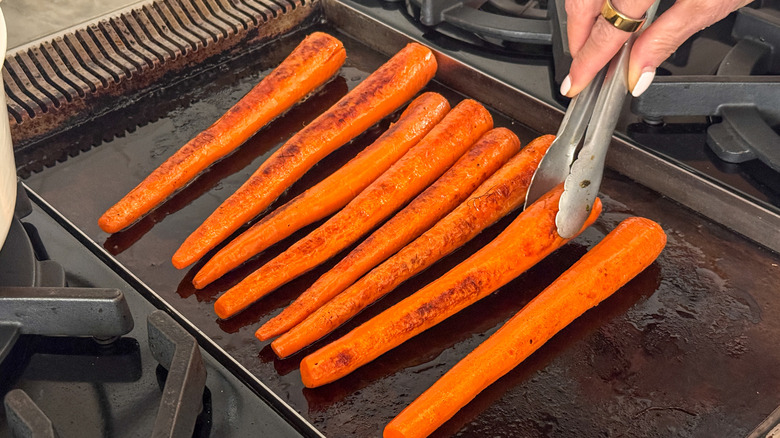 tongs flipping carrot on griddle