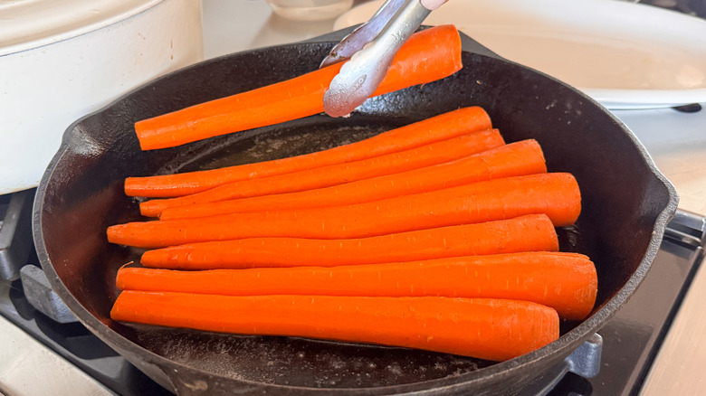 tongs placing carrots in pan