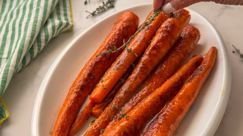 hand adding thyme to carrots