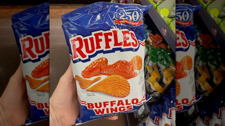 Hand holding bag of Buffalo Wings Ruffles in grocery store