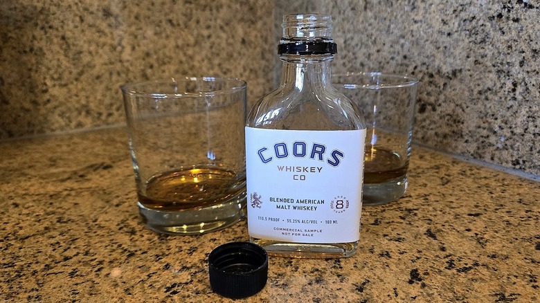 Mini bottle of Coors Whiskey Co. American Blended Malt whiskey with two rocks glasses.