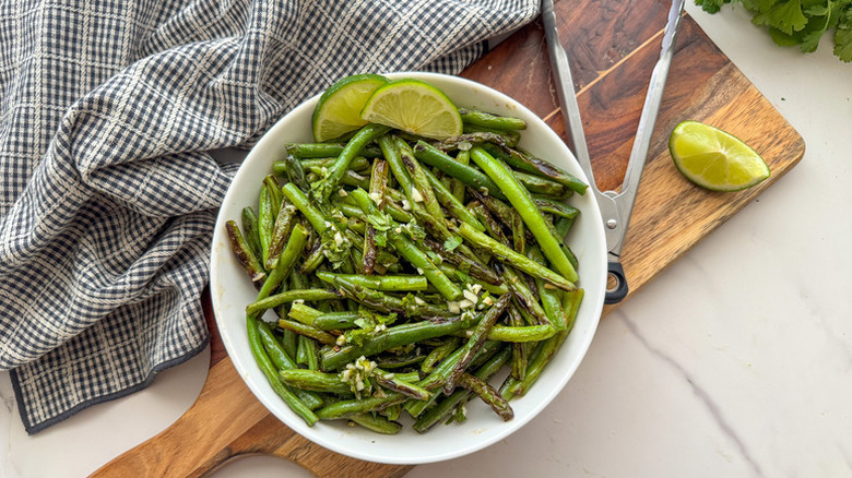 Sauteed green beans in bowl with lime slices