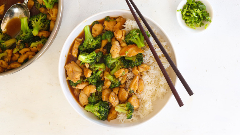 Soy chicken and broccoli in bowl with rice and chopsticks