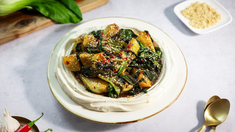 Bowl of stir-fried bok choy on bed of tofu cream