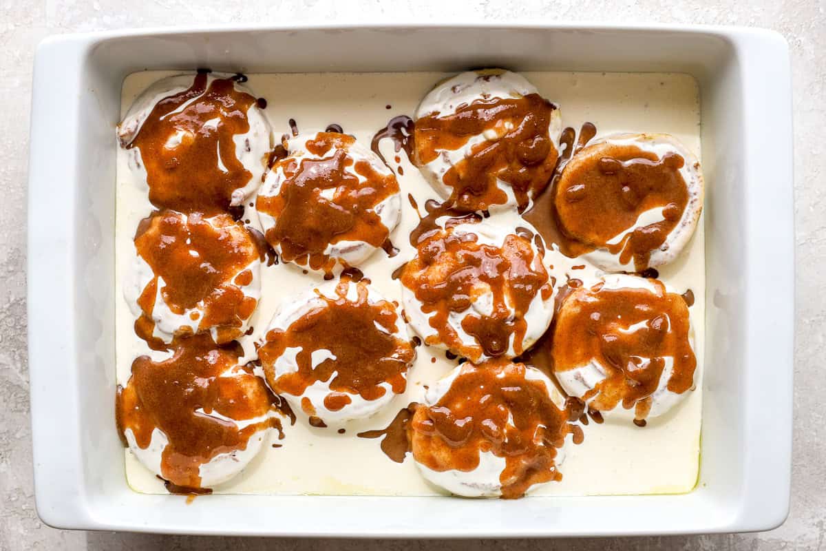 Cinnamon butter mixture drizzled over cinnamon rolls covered in heavy cream before baking.
